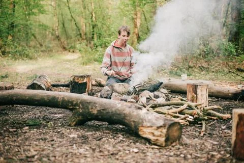 Nomad creating a campfire in spring forest. Stock Photos