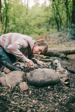 Nomad creating a campfire in spring forest. Stock Photos