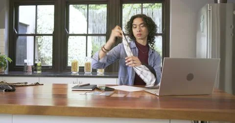 Non-binary adult picking up grid cloth in kitchen, unfolding design, noting, Stock Photos