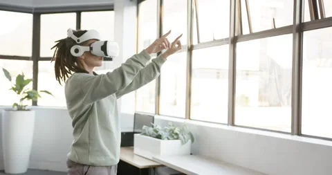 Non-binary African adult with VR headset activating, gesturing selecting by grid Stock Footage 344693555