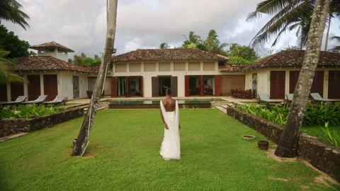 Non-binary black model spinning in wedding dress on tropical villa lawn. Gender Video stock 252774211
