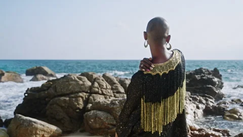Non-binary black person in outrageous gown stands with their back to camera at Stock Footage 275842611
