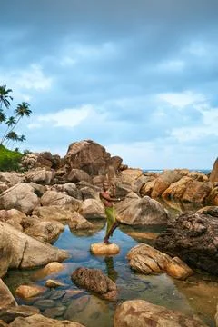 Non-binary black person stands on rock in the middle of still water inside creek Stock Photos