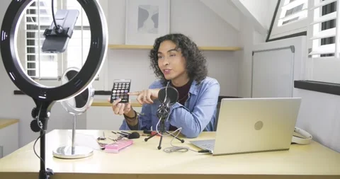 Non-binary creator picking up palette, rotating shades, opening red-lid tube at Stock Footage 339557414