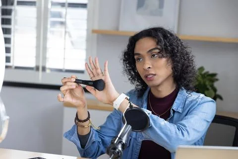 Non-binary creator wearing denim jacket showing makeup brush and speaking toward 写真素材