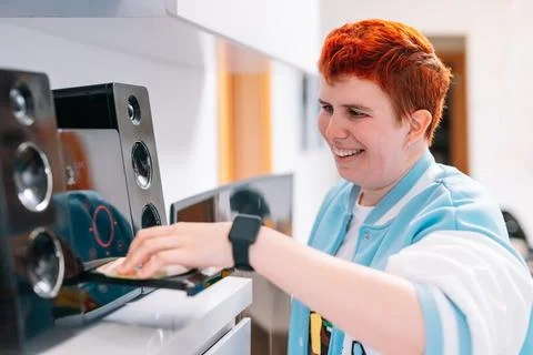 Non-binary gender playing a CD on his mini-system to listen to music. Stock Photos
