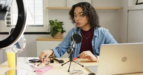 Non-binary host picking mascara tube and examining brushes for tutorial at home Stock Footage 339271886