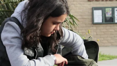 Non binary kid looking for book in backpack Stock Footage 155388032