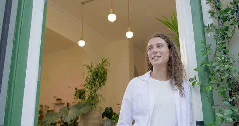 Non-binary late 20s person in white shirt stepping in doorway, laughing as Stock Footage 338436731