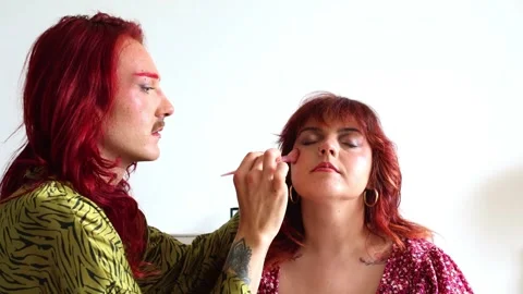 Non-binary makeup artist applying makeup on a curvy model Stock Footage 309130275