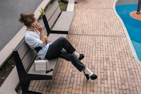 Non-binary man looking around talking using phone in her hands leaning on park Stock Photos