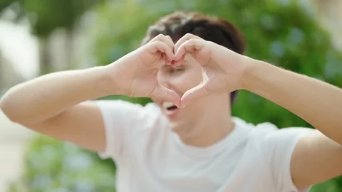 Non binary man smiling confident doing heart gesture with hands at park Video stock 233417465