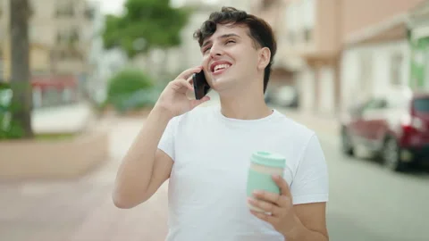 Non binary man talking on smartphone drinking coffee at park Stock Footage 236761132