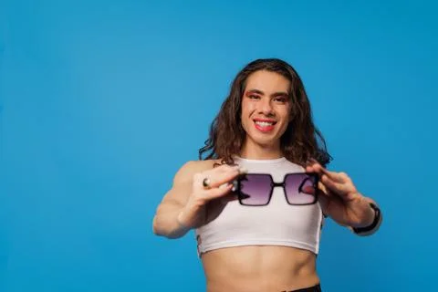 Non-binary or trans men posing with glasses on a blue background and copy spa Stock Photos