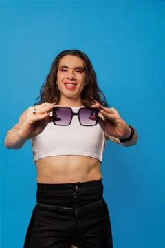 Non-binary or trans men posing with glasses on a blue background and copy spa Stock Photos