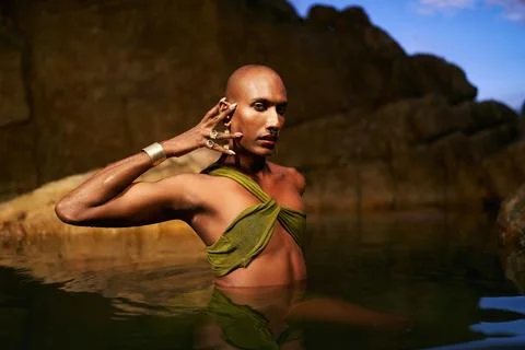 Non-binary person of color poses in water, shows jewelry inside scenic creek at Stock Photos