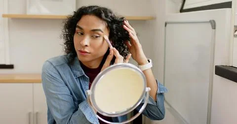 Non-binary person entering frame and applying pink eyeshadow palette with brush Stock Photos