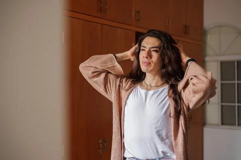 Non-binary person getting dressed in front of the mirror Stock Photos