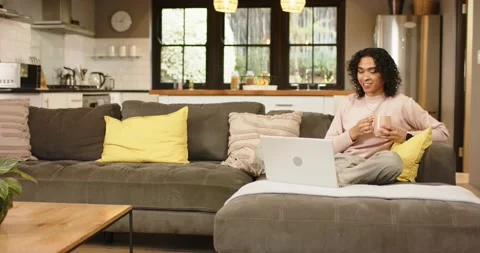 Non-binary person glancing at laptop sipping coffee closing lid to rest leaning Stock Footage 345034887