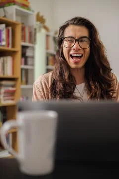 Non-binary person with glasses working from home with a big smile Stock Photos