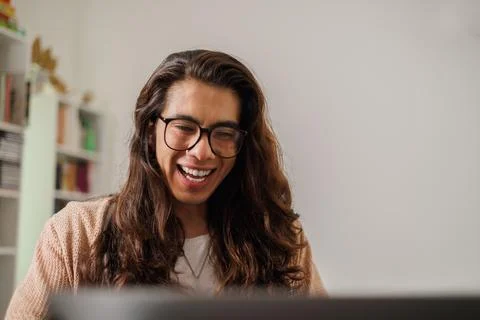 Non-binary person with glasses working from home with a big smile Stock Photos