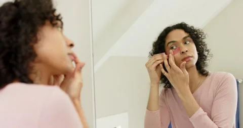 Non-binary person grabbing sponge, dabbing blush before placing gel patch in Stock Footage 344644332