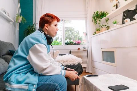 Non-binary person playing video games in the living room at home Stock Photos