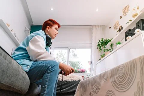 Non-binary person playing video games in the living room at home Stock Photos