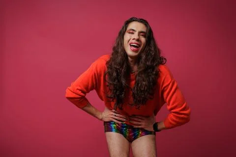 Non-binary person is posing on a red studio background Man has an artistic .. Stock Photos