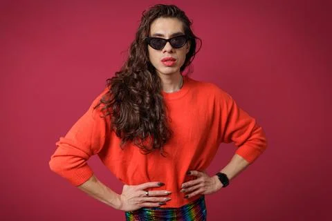 Non-binary person is posing on a red studio background Man has an artistic .. Stock Photos