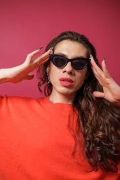 Non-binary person is posing on a red studio background Man has an artistic .. Stock Photos