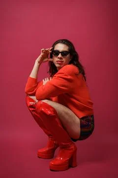 Non-binary person is posing on a red studio background Man has an artistic .. Stock Photos