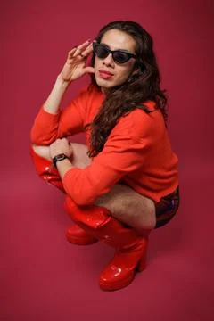 Non-binary person is posing on a red studio background Man has an artistic .. Stock Photos
