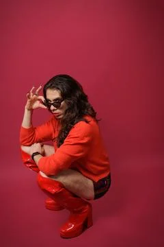 Non-binary person is posing on a red studio background Man has an artistic .. Stock Photos