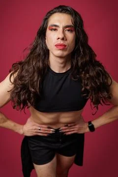 Non-binary person is posing on a red studio background Man has an artistic .. Stock Photos