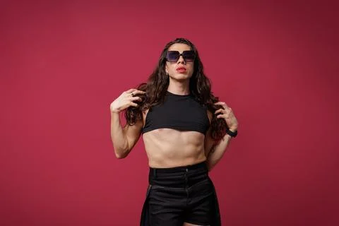 Non-binary person is posing on a red studio background Man has an artistic Stock Photos