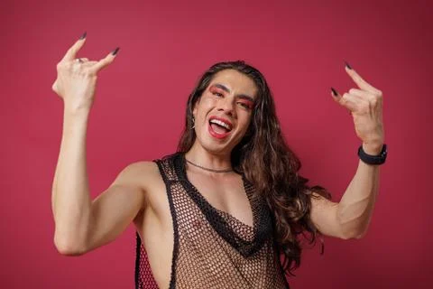Non-binary person is posing on a red studio background Man has an artistic .. Stock Photos
