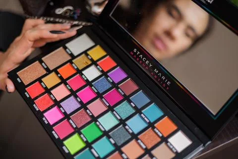 Non-binary person putting makeup on their face before going to work Stock Photos