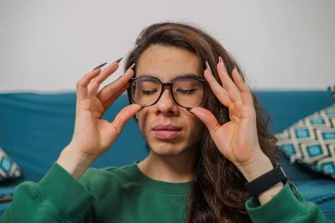 Non-binary person putting on their glasses to start working Stock Photos