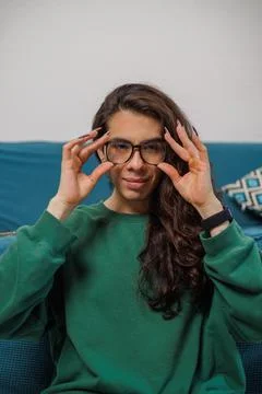 Non-binary person putting on their glasses to start working Stock Photos