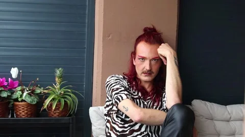 Non-binary person with red hair and mustache posing on balcony Stock Footage 309187484