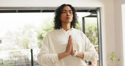 Non-binary person starting meditation pressing palms and breathing on balcony in Stock Footage 339650988