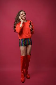 Non-binary person talking on cell phone with a happy expression on their face Stock Photos