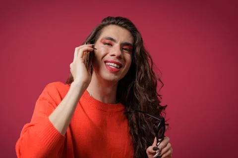 Non-binary person talking on cell phone with a happy expression on their face Stock Photos