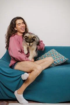 Non-binary person, with their pet on the sofa very happy Stock Photos