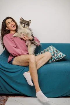 Non-binary person, with their pet on the sofa very happy Stock Photos