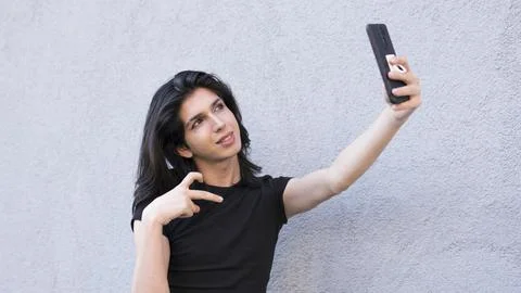 Non-binary person is using a smartphone on the outdoor making a video call Stock Photos