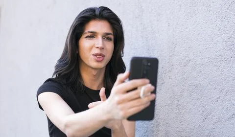 Non-binary person is using a smartphone on the outdoor making a video call Stock Photos