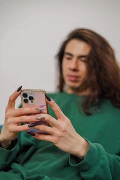 Non-binary person using their cell phone at home with blurred background. L.. Stock Photos