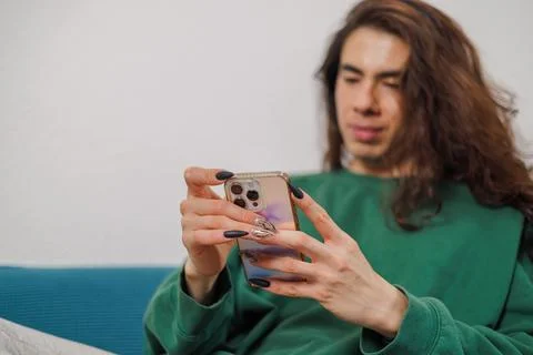 Non-binary person using their cell phone at home with blurred background. L.. Stock Photos
